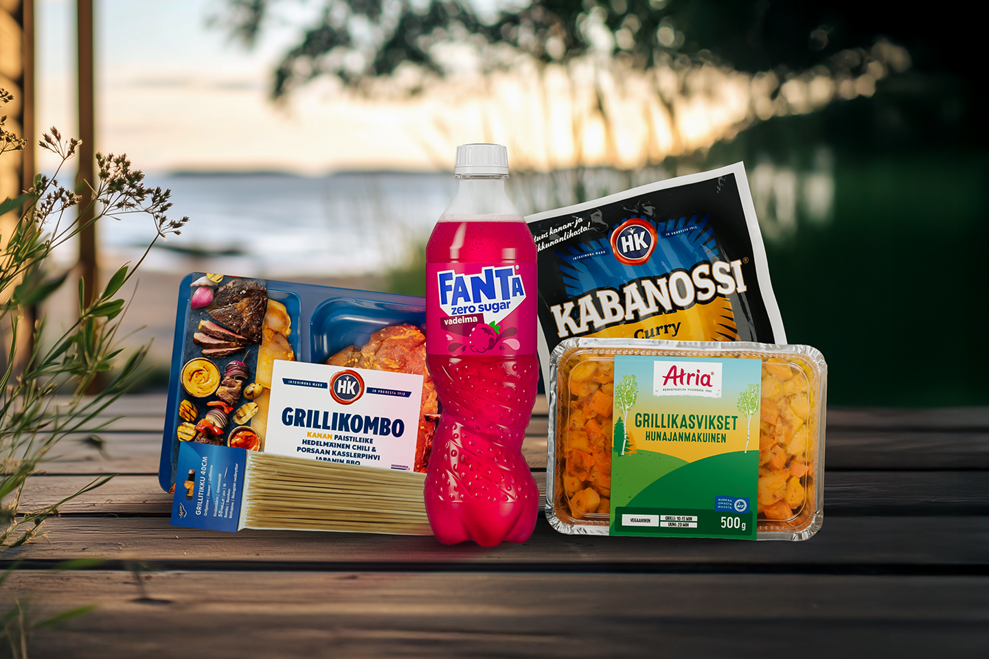 Puuterassilla erilaisia tuotepakkauksia: grillimakkaraa, grillilihaa, grillikasviksia ja virvoitusjuomaa.