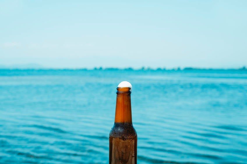 Alkoholiton olutpullo ja taustalla järvi