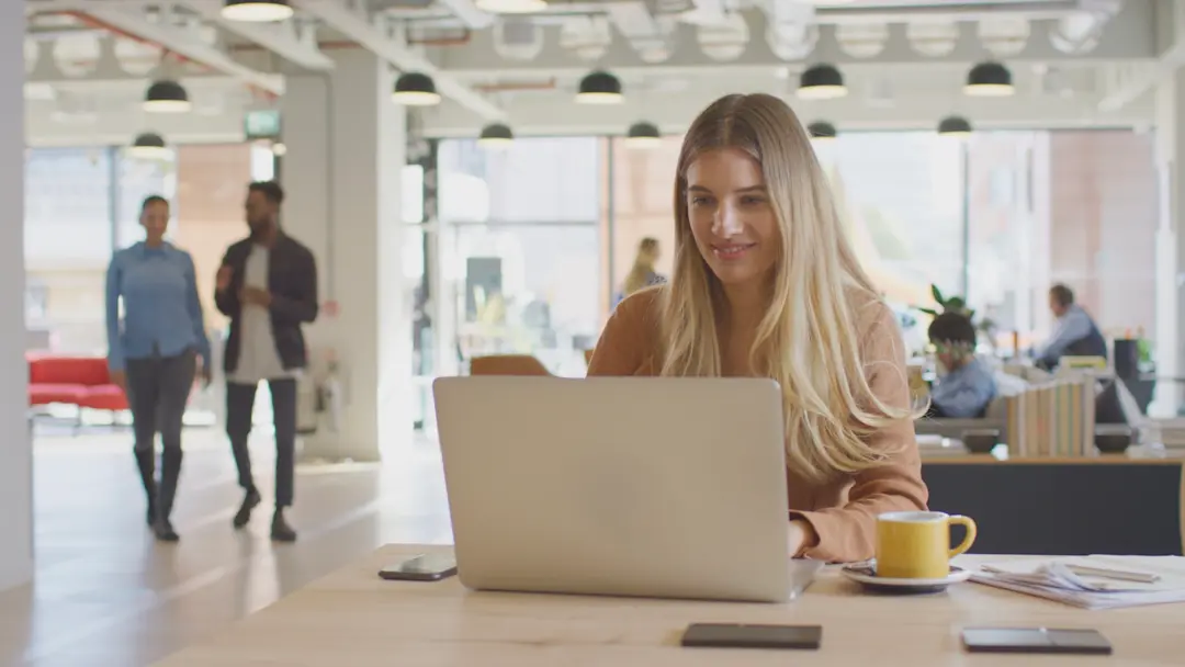 A young woman working on her laptop in an office.