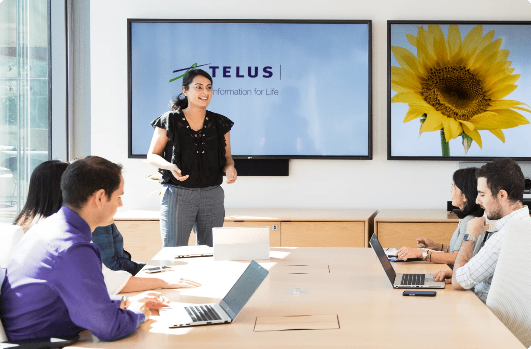 A TELUS team member making a presentation to her team in a meeting room.