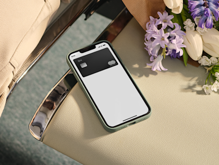 Mobile phone lying on a chair next to some flowers.