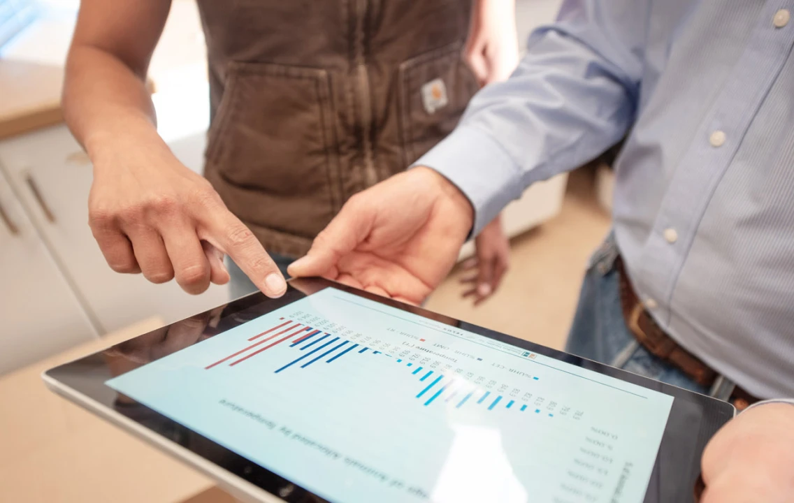A person pointing at a tablet screen with a chart on it.