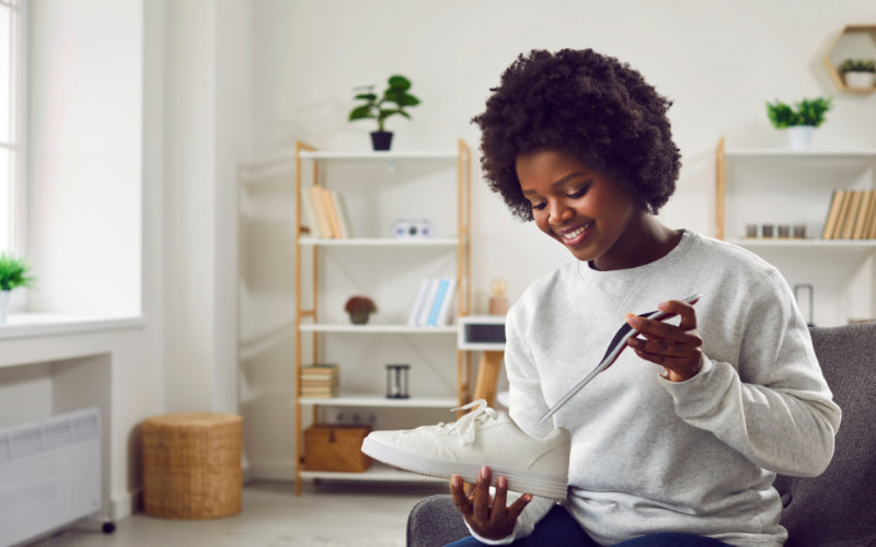 A woman displays a shoe in her hands, emphasizing its design and features for data reporting purposes.